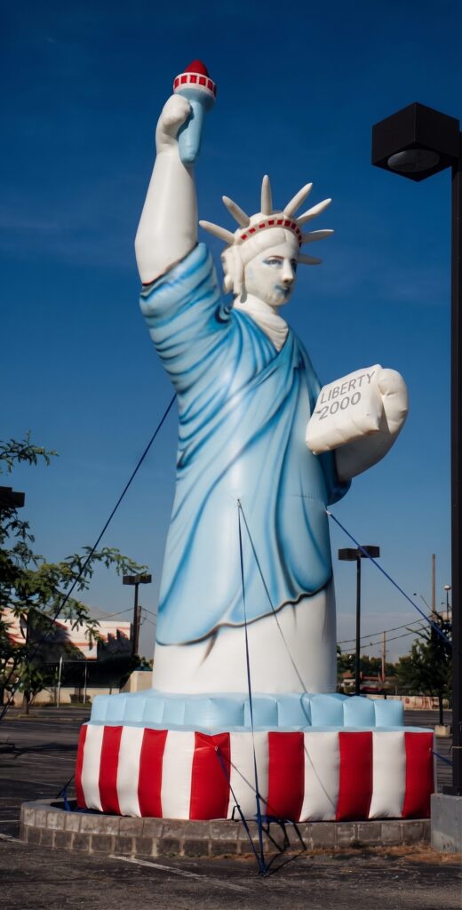 A giant inflatable Statue of Liberty on a red and white striped base
